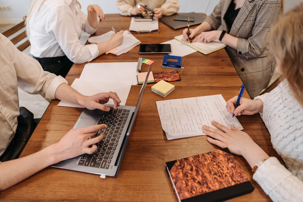 A group of professionals collaborating during a meeting with laptops and notepads.